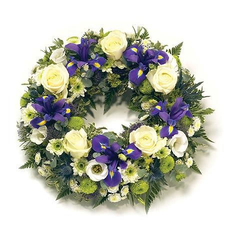 A tastefully arranged funeral wreath with a lush combination of deep purple and pure white flowers.