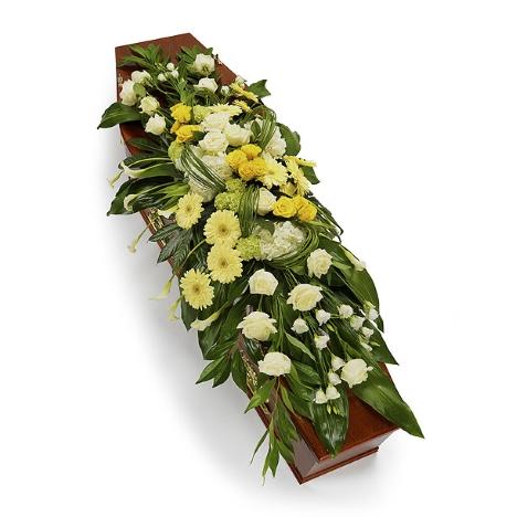 "Yellow and white flowers elegantly arranged in a casket spray tribute."